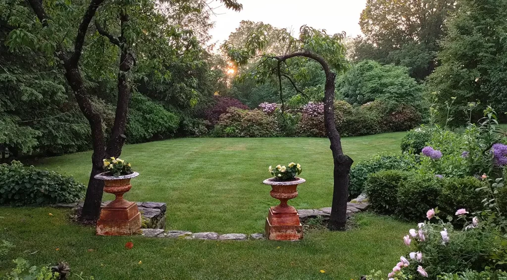 A view of the lawn behind the Abbott Center, featuring two flower filled planters and perennials in bloom.